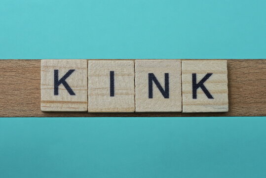 word kink made from wooden gray letters lies on a green background