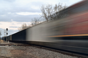 A freight train, blurred by its motion, passing through a crossing with another railroad.