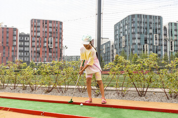 Beautiful little girl playing mini Golf