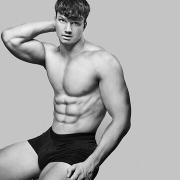 Advertising banner with young handsome caucasian athletic man on gray background. Portrait of man with beautiful athletic body who is dressed boxers and posing near copy space.