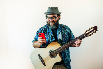 Happy bearded man using smartphone with acoustic guitar.