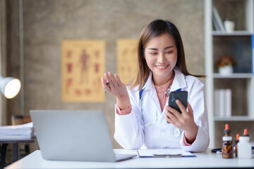 Beautiful Asian doctor woman is having a video call on the phone to discuss drug information, drug details and test results with a smile and confidence.