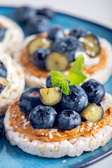 Open sandwich with blueberries. Made from rice crispbreads and peanut butter, healthy nutritious snack option, vegan food