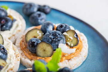 Open sandwich with blueberries. Made from rice crispbreads and peanut butter, healthy nutritious snack option, vegan food
