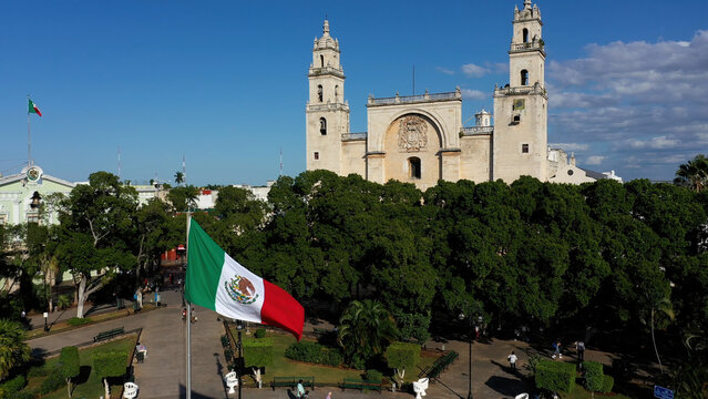 Aerial view in front of Mexican flag waving in front of the cathedral San Ildefonso in Merida, Yucatan, Mexico. - Powered by Adobe