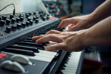composer playing on keyboard synthesizer