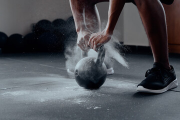 Close-up of young black man doing kettlebell squats with chalk at the gym