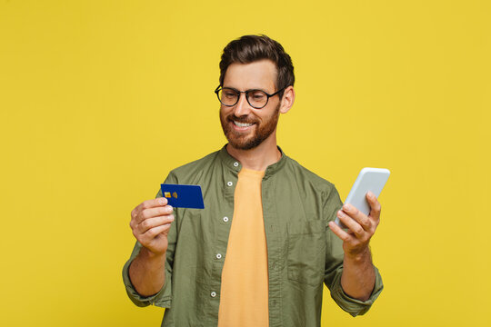 Online wallet concept. Happy middle aged man holding smartphone and credit card, shopping, buying via internet