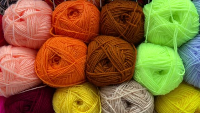 Yarn store display rack of colorful products. Selective focus. Knitting yarn, knitted clothes create coziness.