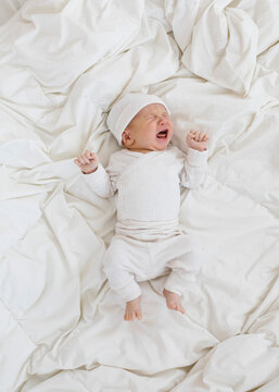 Overhead view of newborn boy (0-1 months) crying on bed