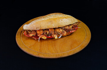 Chicken doner kebab in bread. Doner kebab in bread on wooden board on black background.
