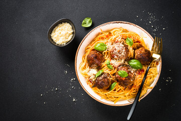 Pasta with beef meatballs in tomato sauce, basil and parmesan cheese on dark stone table. Top view with copy space.