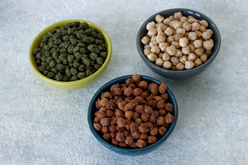 Assortment of dry chickpea piles in bowls. Three different chick pea kinds: green, kala chana and white.