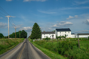 Fototapeta na wymiar Amish houses beside a county road in Holmes County, Ohio on a summer day