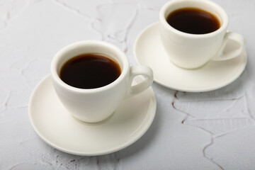 Hot coffee in a white coffee cup on a white texture table in a light atmosphere.Hot warming drink concept.Copy space.Side view.Place for text.