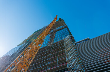 Looking up at the construction site of a high-rise building with a yellow crane