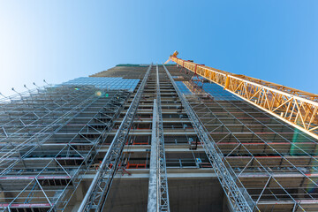 Looking up at the construction site of a high-rise building with a yellow crane