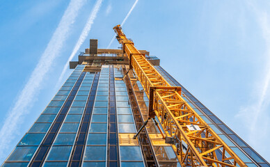 Looking up at the construction site of a high-rise building with a yellow crane - Powered by Adobe