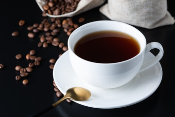 Coffee cup and coffee beans on the black table