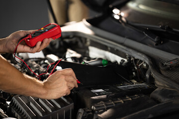 Man using multimeter to measure the voltage of the batteries. Mechanic doing car inspection, he is testing car battery with tester. Check battery voltage with electric multimeter - obrazy, fototapety, plakaty