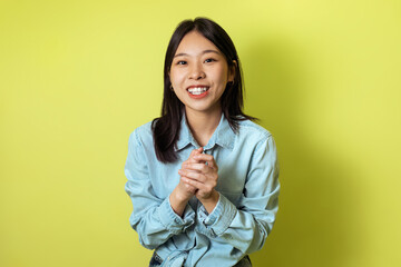 Happy Korean Woman Holding Hands Together Posing Over Yellow Background