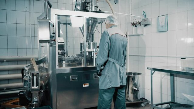 4K Machine operator working on pharmaceutical production line. Automatic Capsule Filling Machine. Automatic production line at a pharmaceutical company. Preparation and production of tablets close-up