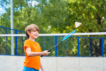 smiling little sportsman playing badminton. joyful child holds a racket in his hand