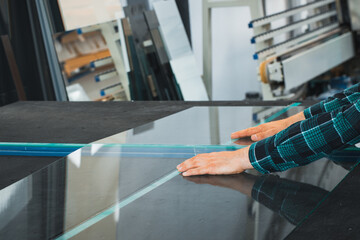 Naklejka premium Glazier breaks a large pane of glass on a special table, Glass factory, Production plant