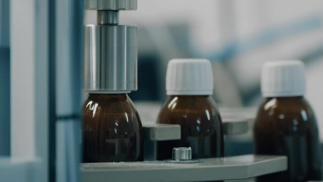 4K Automated production line conveyor in a factory with screw caps on glass bottles. Medical Conveyor Production of Pharmaceuticals. Twist Bottles. Pharmaceutical Industry. Close up, DOF