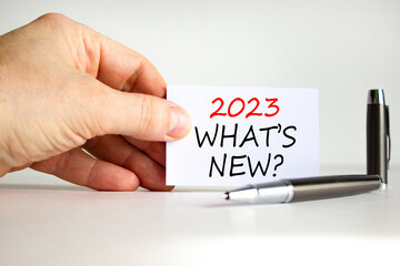 2023 what is new symbol. White card with words 2023 what is new. Businessman hand. Metallic pen....