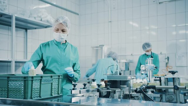 Moscow, Russia - June 26 2022: Women work on the capsule packaging line and put the finished product into a box. Applying labels to bottles. Bottles on a conveyor belt. Production line. Slow motion 4K