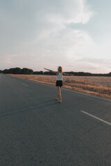 Obraz premium blonde-haired woman walking on the road at sunset in shorts