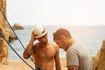 rock climbing instructor teaching young man. summer sports climbing on the beach. Costa Brava....