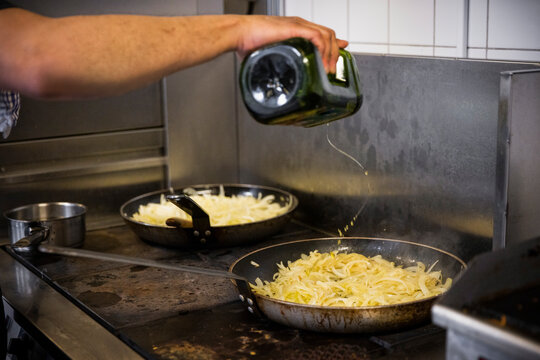 Cropped image of chef pouring oil on food in pan at restaurant kitchen