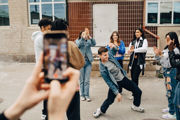 Multiracial men and women applauding while friend dancing on street