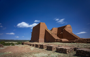 Long exposure image of Pecos National Park ruins with blue sky and moving clouds.