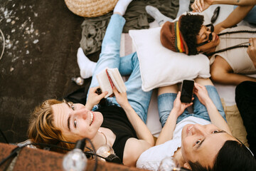 High angle view of male friends sitting by woman lying down