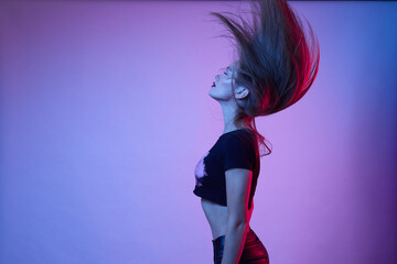 Woman with long hair poses in neon light in the studio.