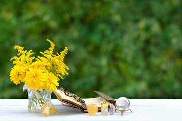 Flowers, witchcraft items, book and crystals on table close up, natural background. Wiccan, Slavic...