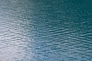 Infinite background of water waves in lake. Blue to black colors. Natural texture.
