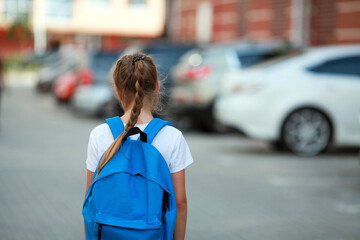 A schoolgirl girl with a briefcase on her back goes to school. Back to school.