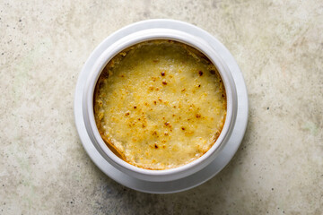 French onion soup with cheese on bowl top view on stone table