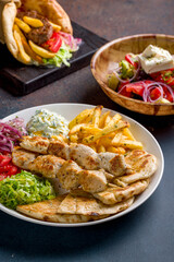 souvlaki with chicken vegetables and pita, greek salad with feta and pita gyros with beef patty and vegetable on dark stone table, selective focus, macro close up, vertical