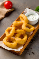 Rings of squid in batter with sauce on brown concrete table macro close up,vertical