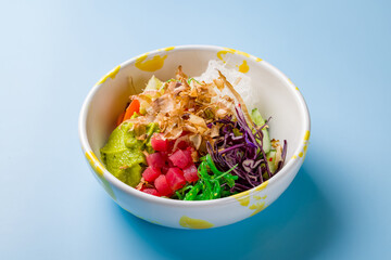 Ahi poke with tuna fresh tomatoes, cucumbers and avocado with chukka and rice on blue background