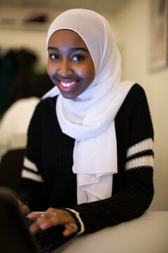 Portrait of smiling girl sitting with laptop in classroom