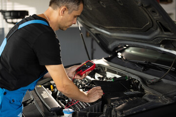 Professional mechanic is working in car service. Good, electrician, electricity, battery charged...