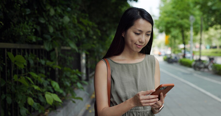 Woman use mobile phone walk at park