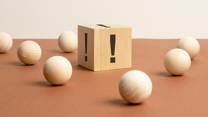 exclamation mark sign on a wooden block on a brown background with wooden balls around