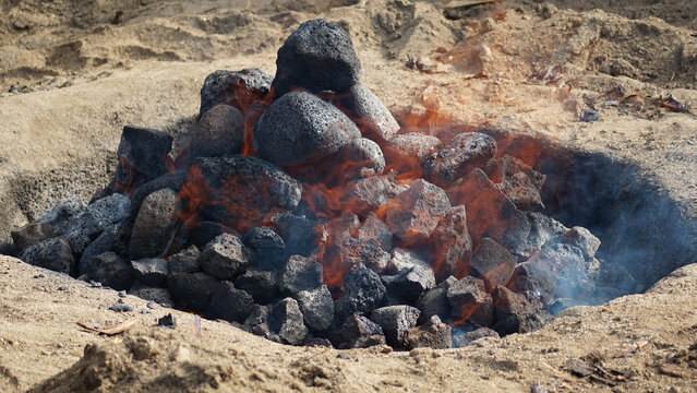 Hot coals and rocks smoldering as the imu is prepared for a luau in Hawaii.